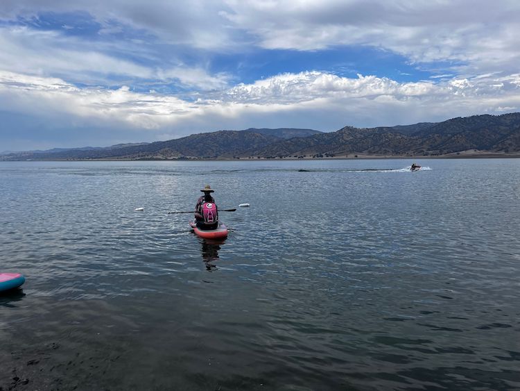A man sitting down on a paddleboard in lak Berryessa