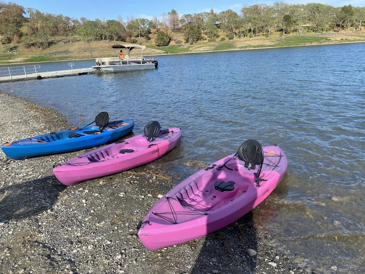 Three kayaks on the shore of the lake.