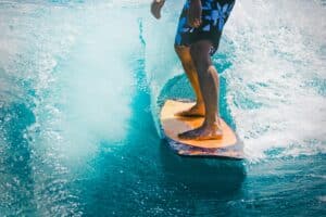 Image of a wake surfer riding a wave. View shows only legs down on a clear blue wave